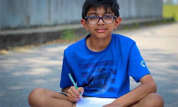 student smiles at camera while writing